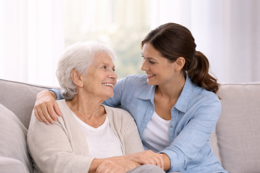 Caregiver supporting elderly woman at home to promote independence and comfort.